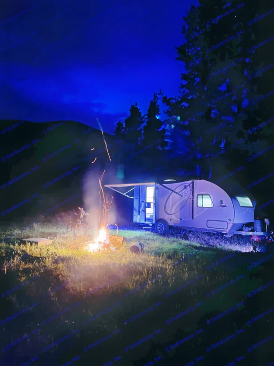 Night camping with an RV rental: a cozy campfire, bicycle, and blue-lit trailer under a deep blue sky.. R-Pod Hood River Edition 2020