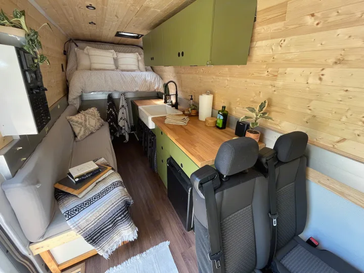 Cozy camper van RV rental interior features a kitchen, bed, and wood paneling. Ideal for travel and adventure.. Freightliner Sprinter 2010