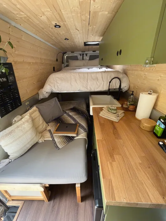 Step inside this cozy RV rental's light wood interior. Features a comfortable bed, a functional kitchen, and a lounge area.. Freightliner Sprinter 2010