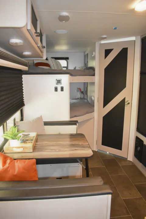 Modern rv rental interior with bright bunk beds, a cozy dining table, and sleek overhead storage, ready for your next adventure.. Heartland RVs Mallard 2022