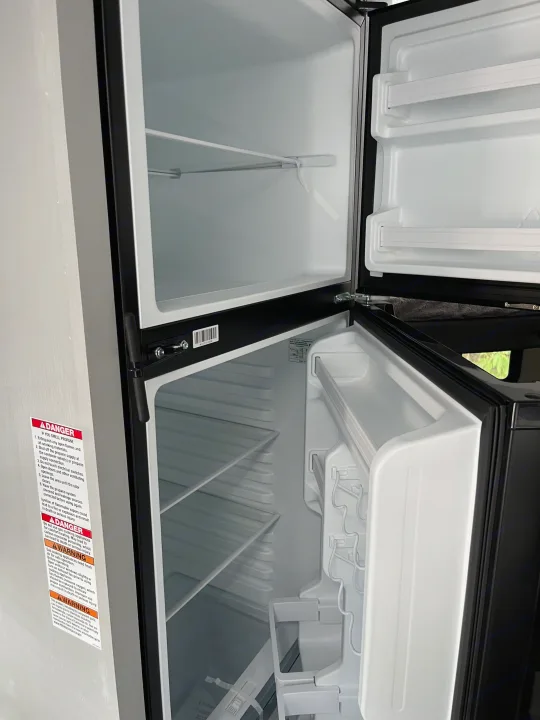 RV rental: An empty, clean two-door refrigerator, with doors open, ready for your trip supplies.. Forest River Wildwood FSX 2022
