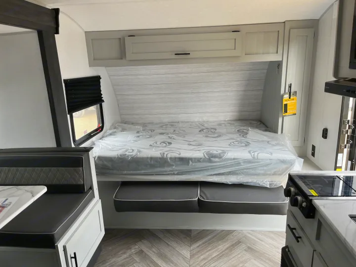Clean RV rental interior: new bed (plastic-wrapped), dinette, & compact kitchen. Ready for your next adventure.. Forest River Wildwood FSX 2022