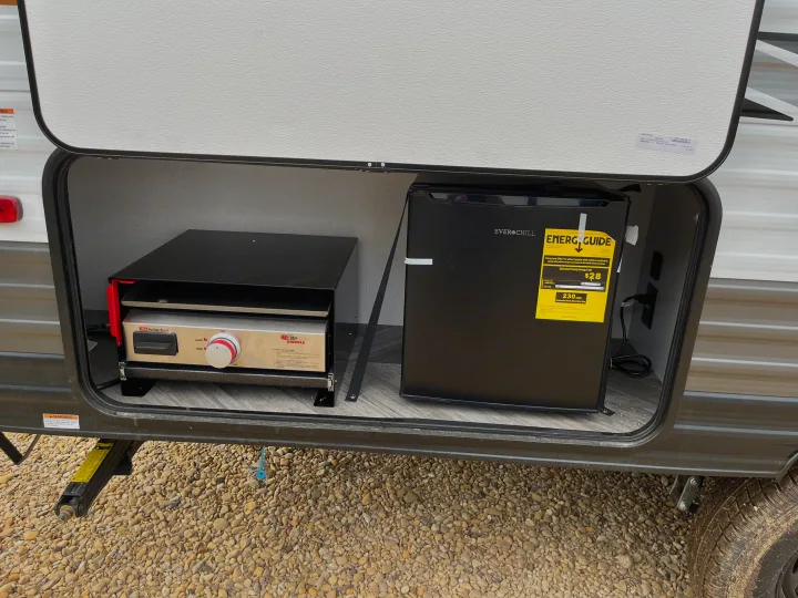Outdoor kitchen in an RV rental, featuring a Suburban griddle and EverChill mini-fridge with an Energy Guide label.. Forest River Wildwood FSX 2022