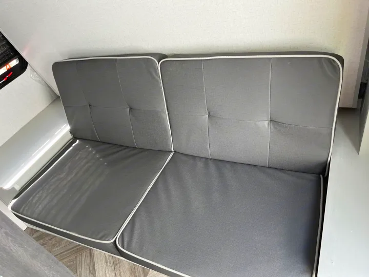 Grey dinette seating in an RV rental. Cushions with white piping are ideal for compact RV interiors.. Forest River Wildwood FSX 2022