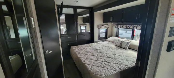 Step inside this modern RV rental bedroom, featuring a comfortable bed, mirrored closet, and ample storage for your adventures.. Jayco Greyhawk 2021