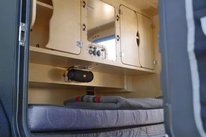 Inside this cozy RV rental, light wood cabinets, power outlets, a mounted JBL speaker, and a comfy bed offer convenience for travel.. Oregon Trail'R TerraDrop ALPHA 2022