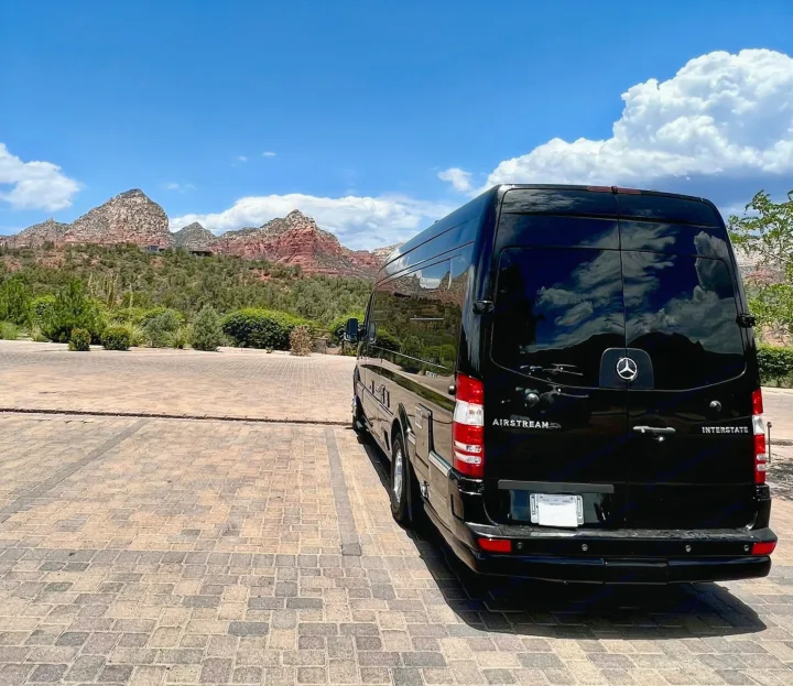 Black Airstream Interstate RV rental parked on a paved lot with stunning red rock mountains under a blue sky.. Airstream Interstate 2016