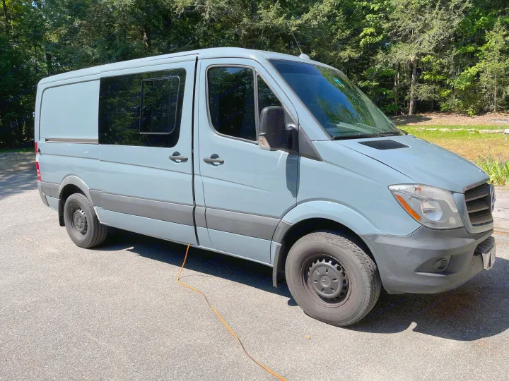 A light gray Mercedes-Benz Sprinter camper van, an ideal RV rental. Parked on asphalt outdoors with trees in the background.. Mercedes-Benz B class campervan MB 140 2014