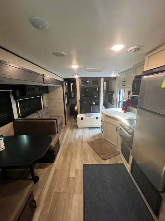 Inside a modern rv rental: full kitchen, dining nook, and comfy sofa in a well-lit living space.. Jayco Jay Flight SLX 2022