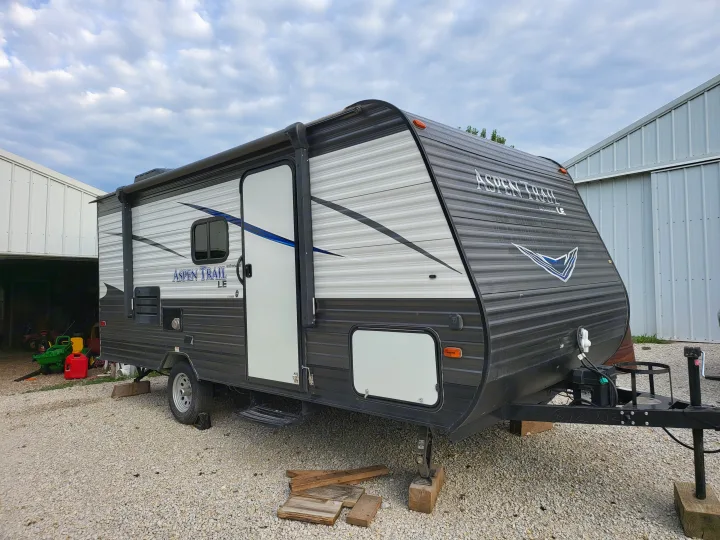 Modern gray & white Aspen Trail LE travel trailer (RV) on gravel. Perfect for an RV rental adventure or family trip.. Aspen Trail LE 2020