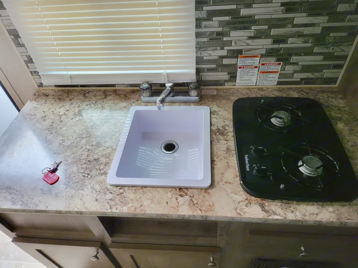 RV rental travel trailer kitchen featuring a modern sink, Suburban stovetop, and ample counter space for road trips.. Aspen Trail LE 2020