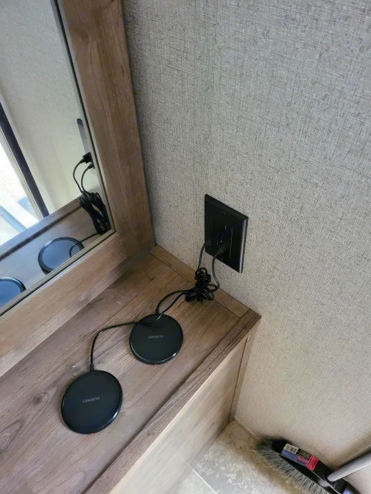 RV rental interior: Wall-mounted USB outlet powers two COKOEYE wireless chargers on a wood cabinet.. Aspen Trail LE 2020