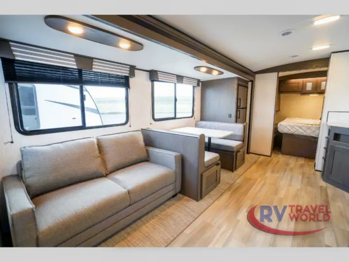Modern RV rental interior: comfortable living space with a sofa, dinette, and bedroom. Light wood-look floors throughout.. Cruiser RV MPG Ultra Lite 2022