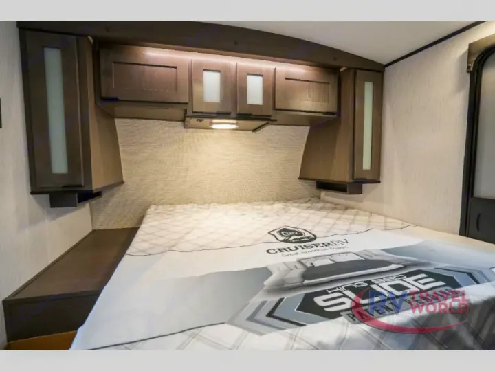 Cozy RV rental bedroom with modern overhead cabinets, task lighting, a comfortable bed, and convenient bedside storage.. Cruiser RV MPG Ultra Lite 2022