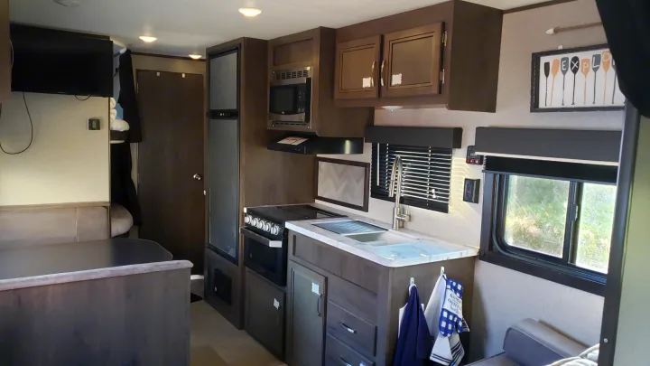 RV rental interior features a compact kitchen, comfortable dinette, and living area with a TV.. Jayco Jay Flight SLX 2019