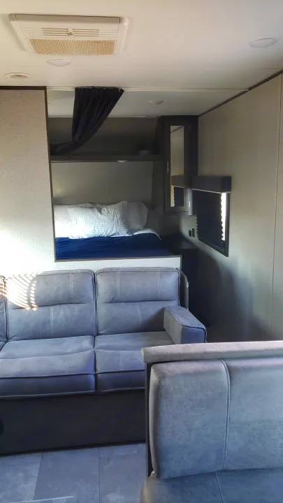 Spacious RV rental interior featuring a comfy gray sofa, bunk bed, and modern lighting. Perfect for travel adventures.. Jayco Jay Flight SLX 2019