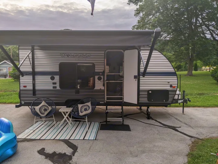 Relaxing RV rental patio with awning, outdoor seating, and rug for comfortable camping. Perfect for travel trailer adventures.. Forest River Cherokee Wolf Pup 2019