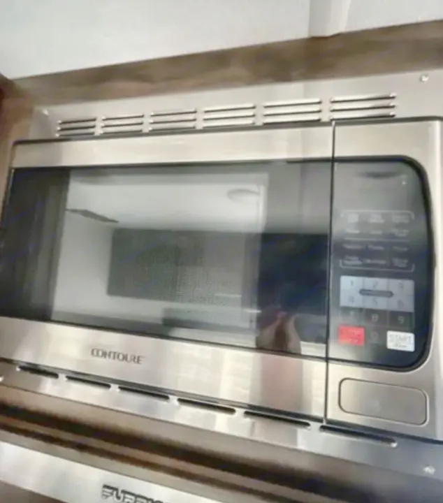 Stainless steel Contoure microwave oven for your RV rental. A modern kitchen appliance for easy travel meals.. Forest River Cherokee Wolf Pup 2019