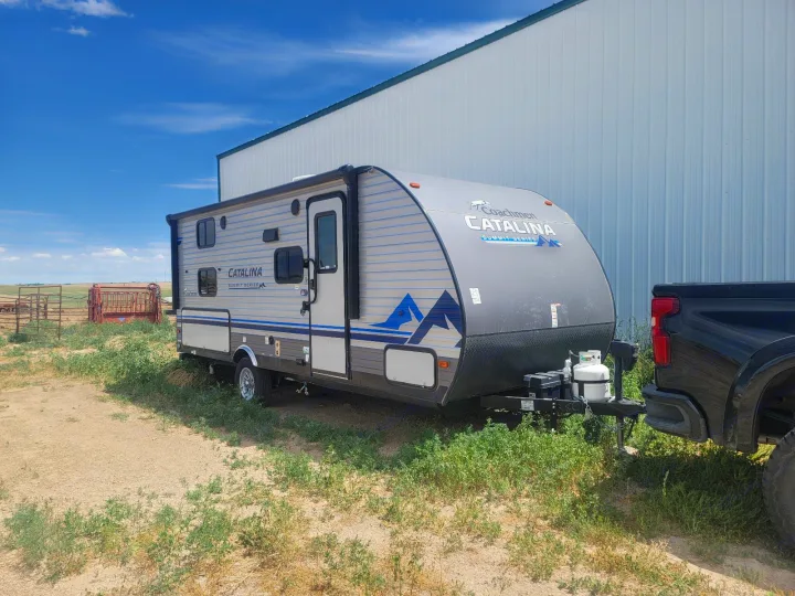 Light gray Coachmen Catalina RV rental, hitched to a truck, ready for outdoor adventures like camping. Bright blue sky overhead.. Coachmen Other 2021