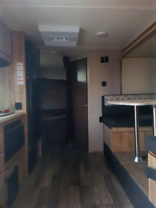 Inside an RV rental: kitchen counter, bunk beds, dinette with table, and ceiling AC unit. Wood-look floor.. Coachmen Other 2021