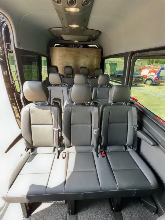 Bright interior of an RV rental van featuring many rows of dark passenger seats. Ideal for comfortable group transport.. Mercedes-Benz Sprinter 2022