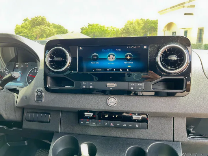 RV rental interior: Mercedes-Benz dashboard with large infotainment screen displaying phone options, plus modern climate control.. Mercedes-Benz Sprinter 2022