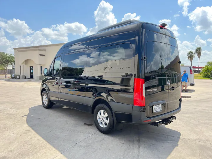 A shiny black Mercedes-Benz Sprinter van, a versatile RV rental ready for adventure under a bright sky.. Mercedes-Benz Sprinter 2022