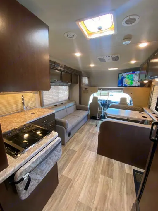 Bright RV rental interior with kitchen, sofa, dinette, and overhead bunk. Enjoy comfortable road trips.. Thor Freedom Elite 2020