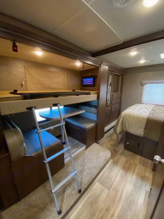 RV rental interior: bunk beds with ladder, lower dinette, and master bed section. Ample living and sleeping space for travelers.. Thor Freedom Elite 2020