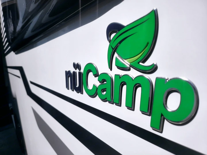 The nuCamp RV rental branding on a white camper. The 3D logo, with green letters and leaf, highlights quality travel.. Nucamp Tab 400 2022