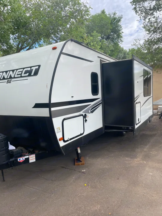 Detailed view of a white Connect SE travel trailer RV rental, slide-out extended, parked on pavement.. Connect SE 2021