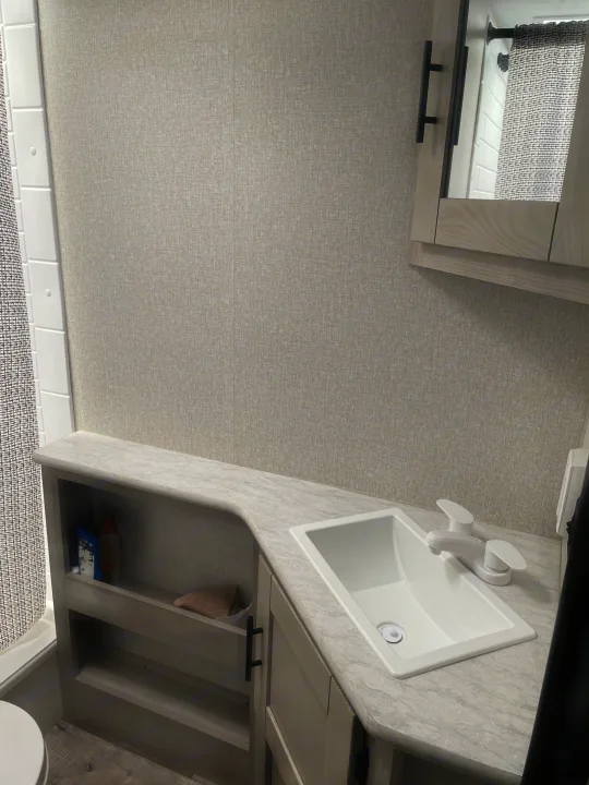Modern RV rental bathroom features light grey walls, white sink, light wood cabinetry, and shower.. Connect SE 2021