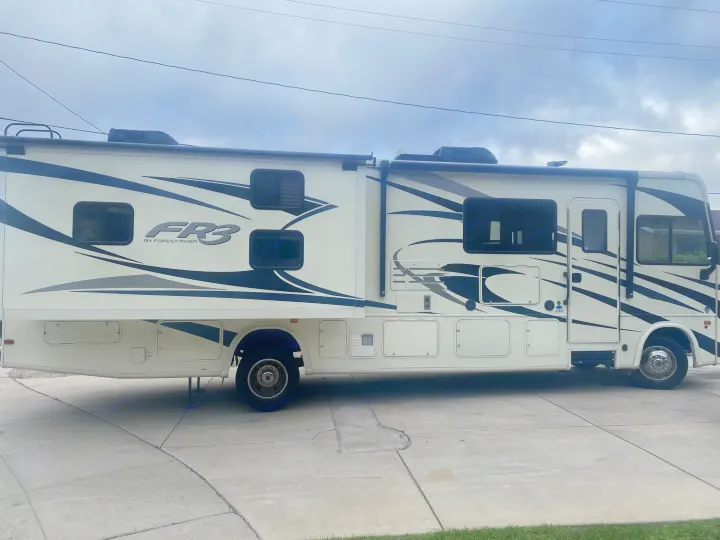 Side view of a white FR3 by Forest River RV with dark graphics, parked on concrete.. FR3 FR3 Motorhome 2020