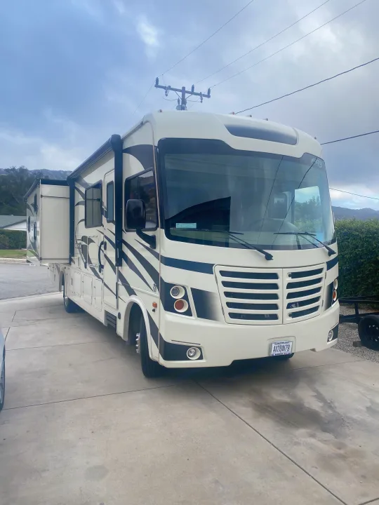 White motorhome RV rental, parked on a driveway with its side expanded, beneath a cloudy sky.. FR3 FR3 Motorhome 2020