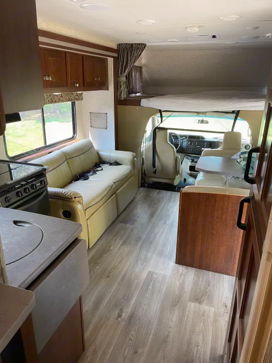 Spacious RV rental interior with a cozy living area, kitchen, and overhead bunk, perfect for travel.. Forest River Sunseeker 2017