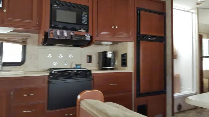 Explore this well-equipped RV rental kitchen: fridge, microwave, stove, coffee maker, and wood cabinets. Ready for your adventure!. Winnebago Chalet 2013