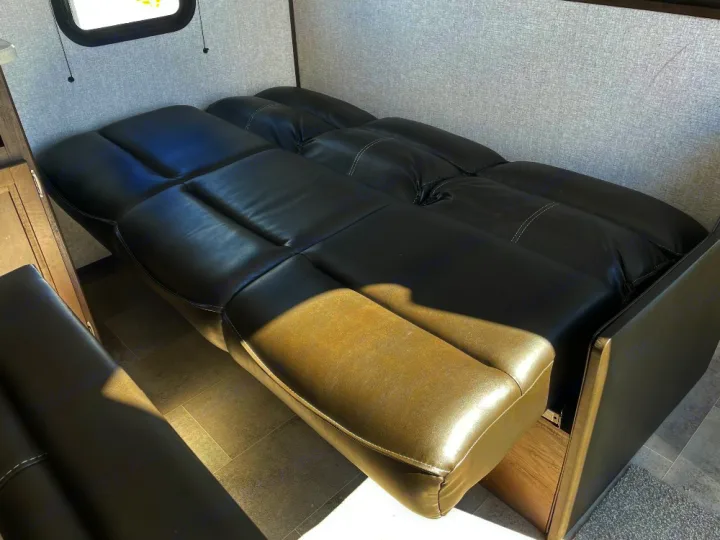 Inside an RV rental, a multi-section black leather sofa converts to a bed, offering versatile seating and sleeping.. Dutchmen Coleman Lantern LT 2022