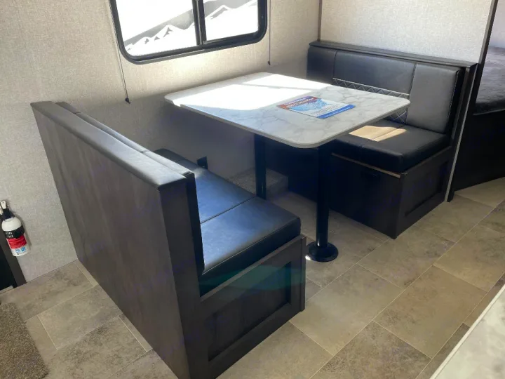 Spacious RV rental dinette with black booth seating and white table.. Dutchmen Coleman Lantern LT 2022