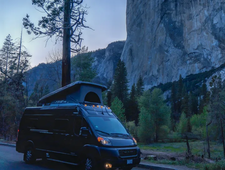 RV rental van with pop-top under El Capitan at dusk in Yosemite National Park, ready for adventure.. Winnebago Solis 59PX 2023