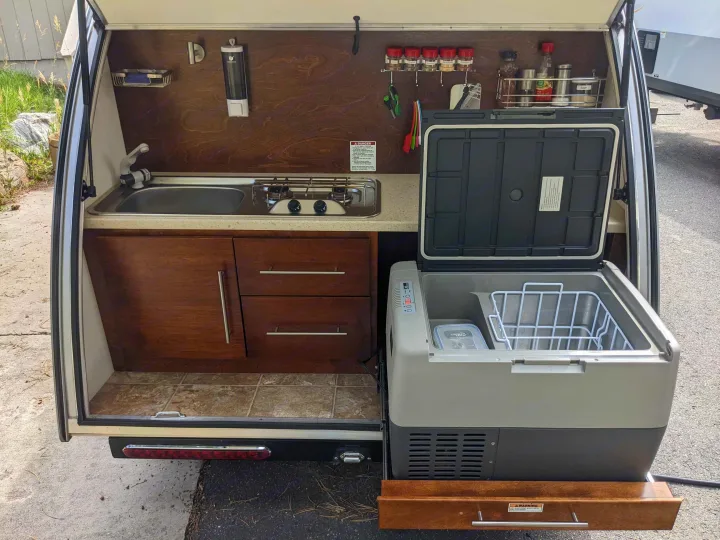 This RV rental features a compact mobile kitchen with a sink, stove, fridge, and ample storage, perfect for any adventure.. T@G T@G Trailer 2016