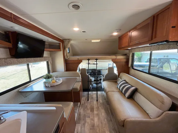 Spacious RV rental interior features a dinette, comfortable sofa, kitchen, and overhead bunk bed.. Winnebago Minnie Winnie 2017
