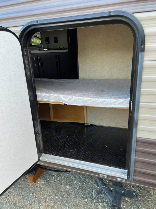 Inside an RV rental: view through the open door showing the sleeping area, kitchen, and black diamond plate floor.. Forest River Cherokee Wolf Pup 2018