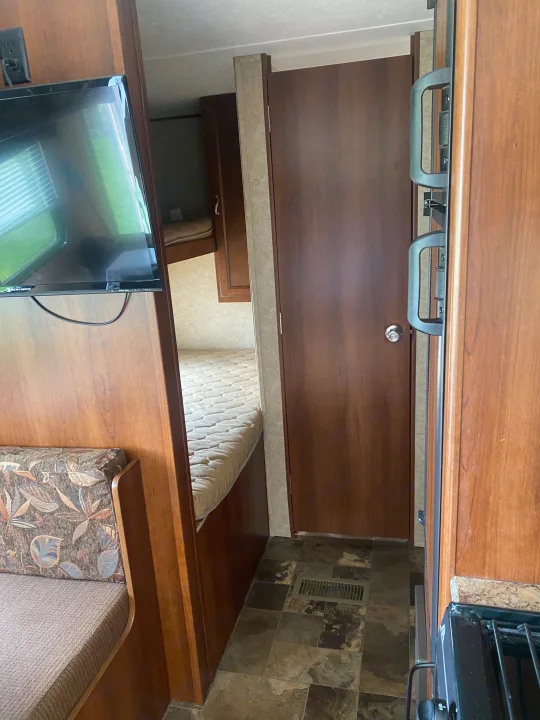 Cozy RV rental interior shows a dinette, TV, bunk beds, and kitchen for your travel adventures.. Avenger ATI 2015