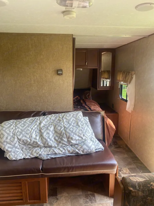 Inside a cozy rv rental: living area with sofa and patterned blanket, plus a compact bedroom, perfect for journeys.. Avenger ATI 2015