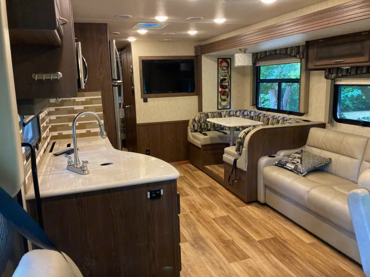 Bright RV rental interior featuring a full kitchen, U-shaped dinette, entertainment TV, and plush sofa.. Forest River Coachmen Mirada 2019
