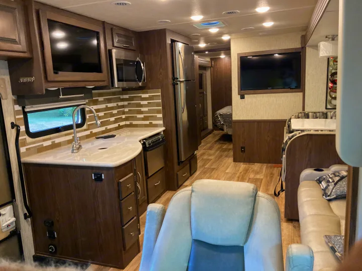 Spacious RV rental interior: A well-equipped kitchen, inviting living area with TV, and a cozy bedroom are visible.. Forest River Coachmen Mirada 2019