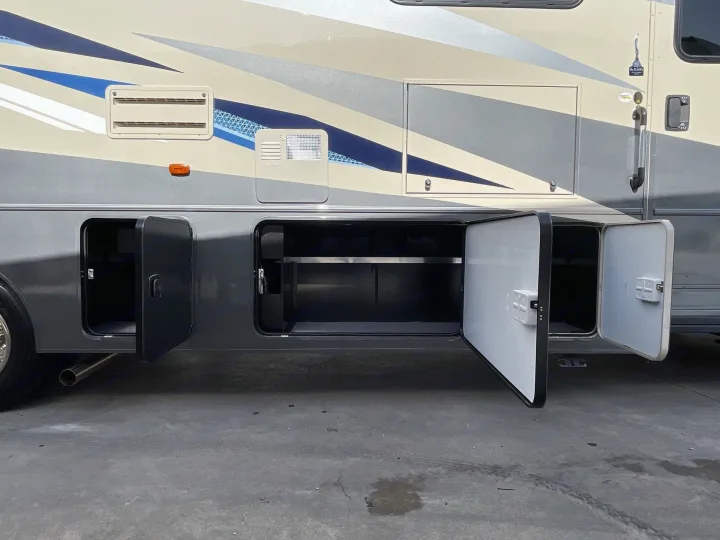 Side of a motorhome RV rental with all exterior storage compartments open, revealing spacious undercarriage storage.. Winnebago Sunstar 2022