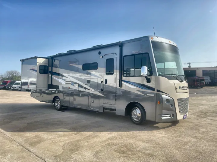 Modern gray Winnebago motorhome with slide-out extended, parked on concrete. Perfect for your next RV rental adventure.. Winnebago Sunstar 2022