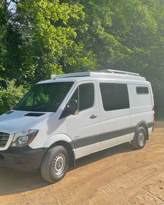 This white Mercedes-Benz Sprinter camper van, with solar, on a dirt road. Ready for your next RV rental adventure!. Freightliner Sprinter 2015