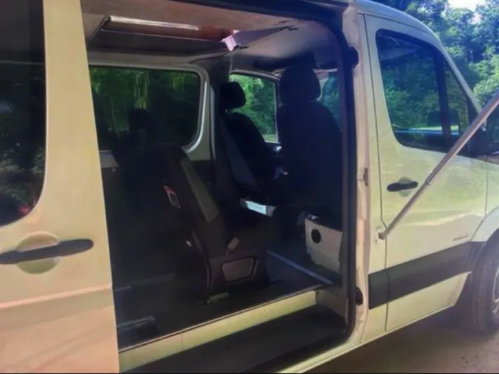 White van RV rental with open side door reveals passenger seating & spacious interior for travel.. Freightliner Sprinter 2015